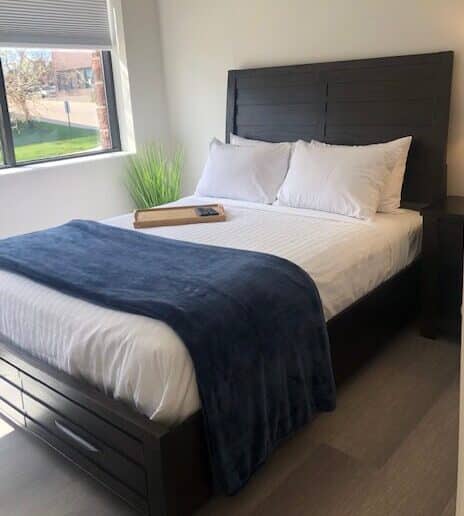 single bed shown in Denver Detox Center patient room with view of grass and trees out the window